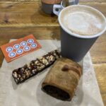 Sweet potato sausage roll, salted caramel nut bar and cappuccino at the Revolution Cafe in Moreton-in-Marsh, Gloucestershire
